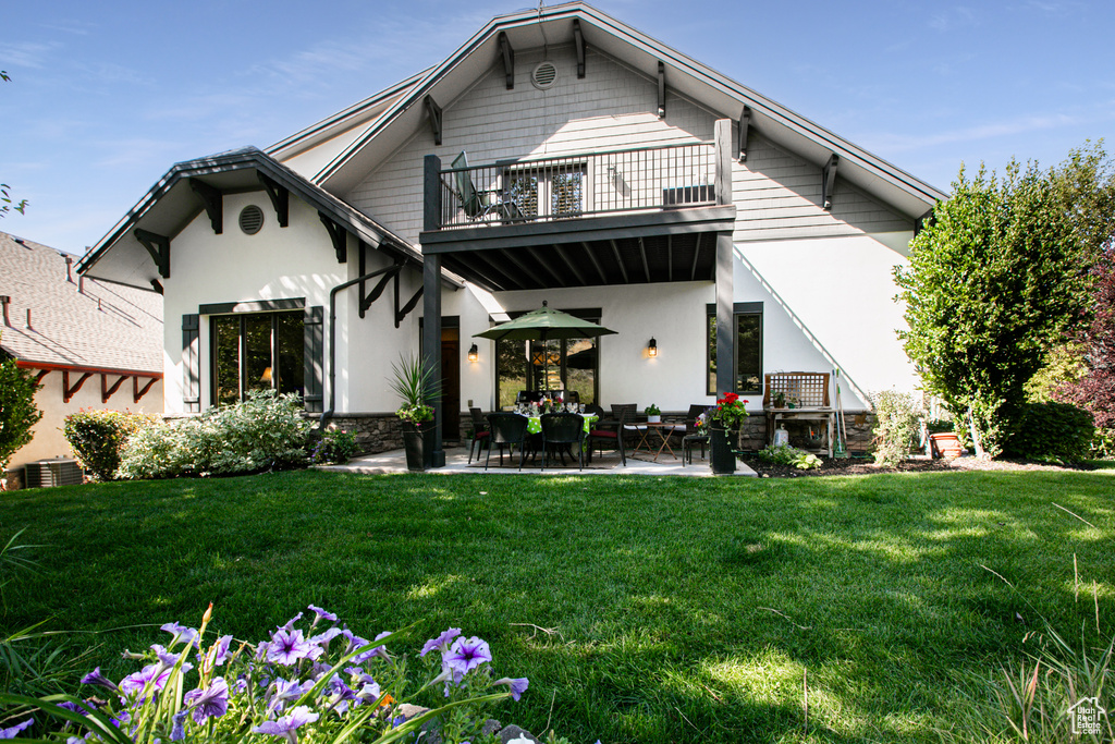 Back of property with a balcony, a patio area, a lawn, and cooling unit