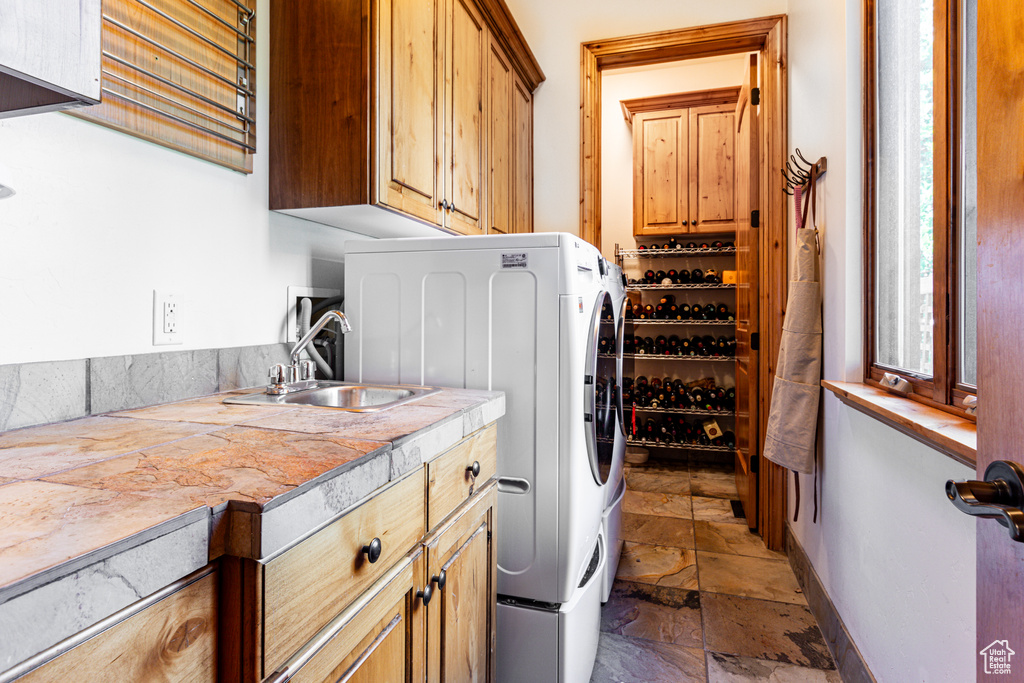 Clothes washing area with wet bar, cabinets, and washer / clothes dryer