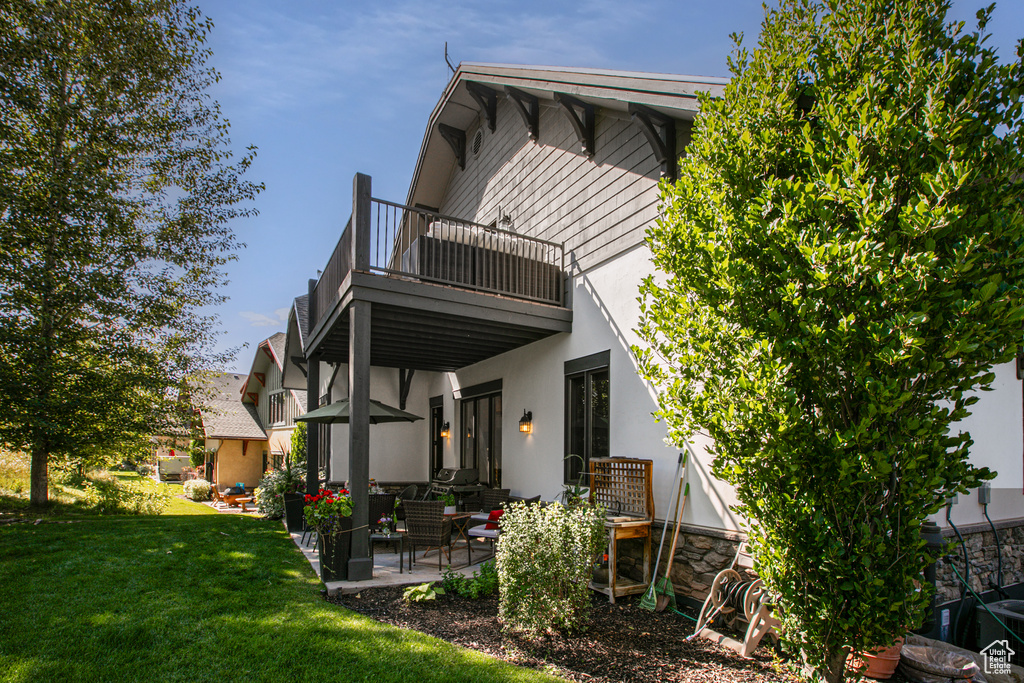 Rear view of house with a yard, a patio, and a balcony