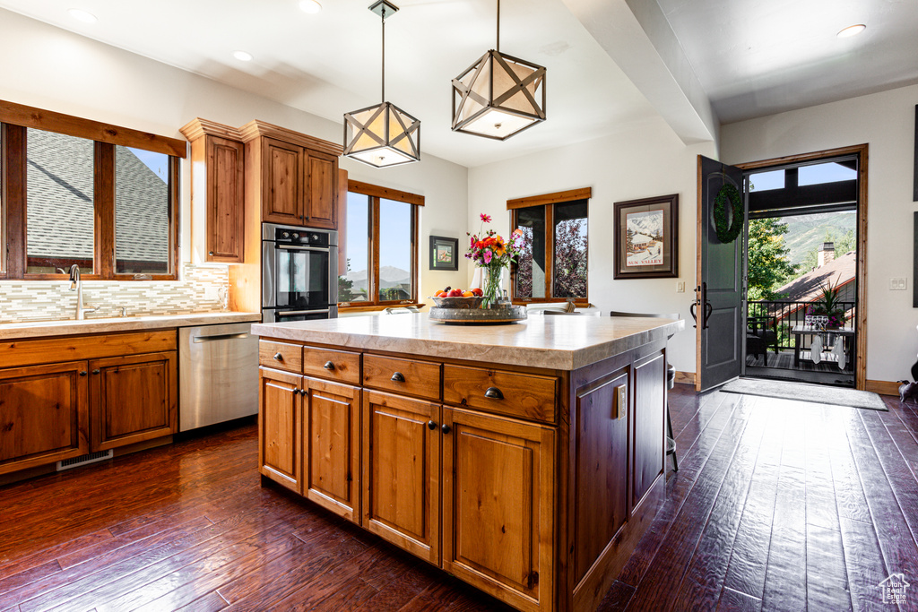 Kitchen with appliances with stainless steel finishes, a center island, dark hardwood / wood-style floors, and plenty of natural light