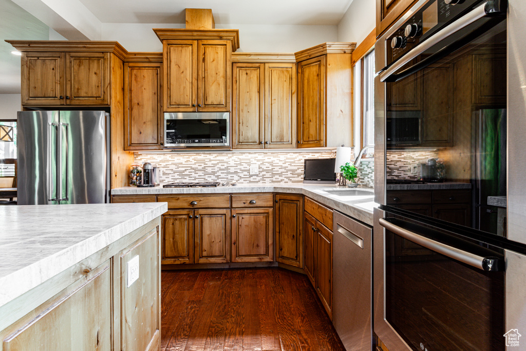 Kitchen featuring stainless steel appliances, dark hardwood / wood-style floors, sink, and decorative backsplash