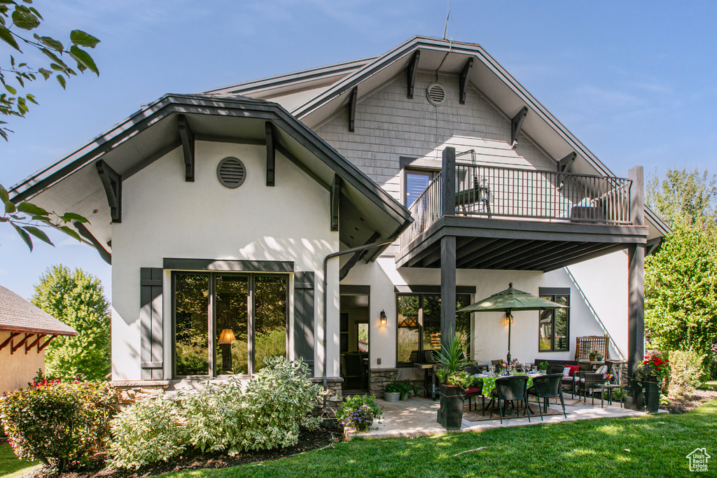 Rear view of house featuring a balcony, a yard, and a patio area