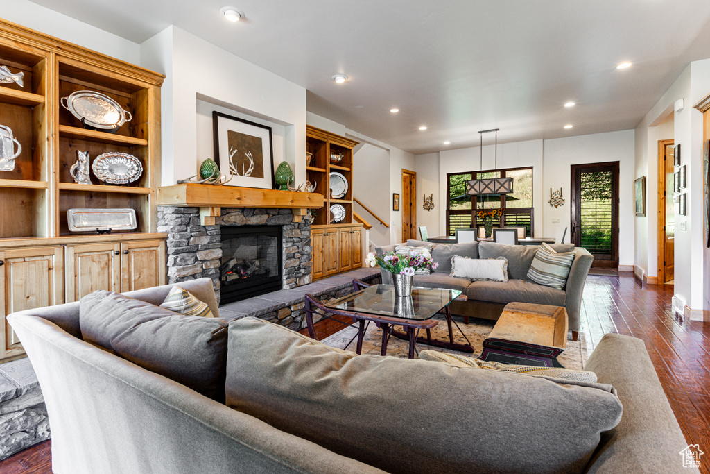 Living room featuring dark hardwood / wood-style floors and a stone fireplace