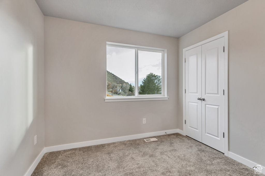 Unfurnished bedroom with a closet and light carpet