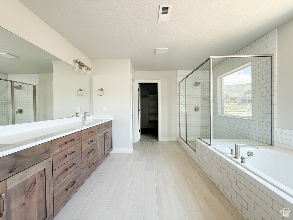 Bathroom with a shower stall, double vanity, and a garden tub