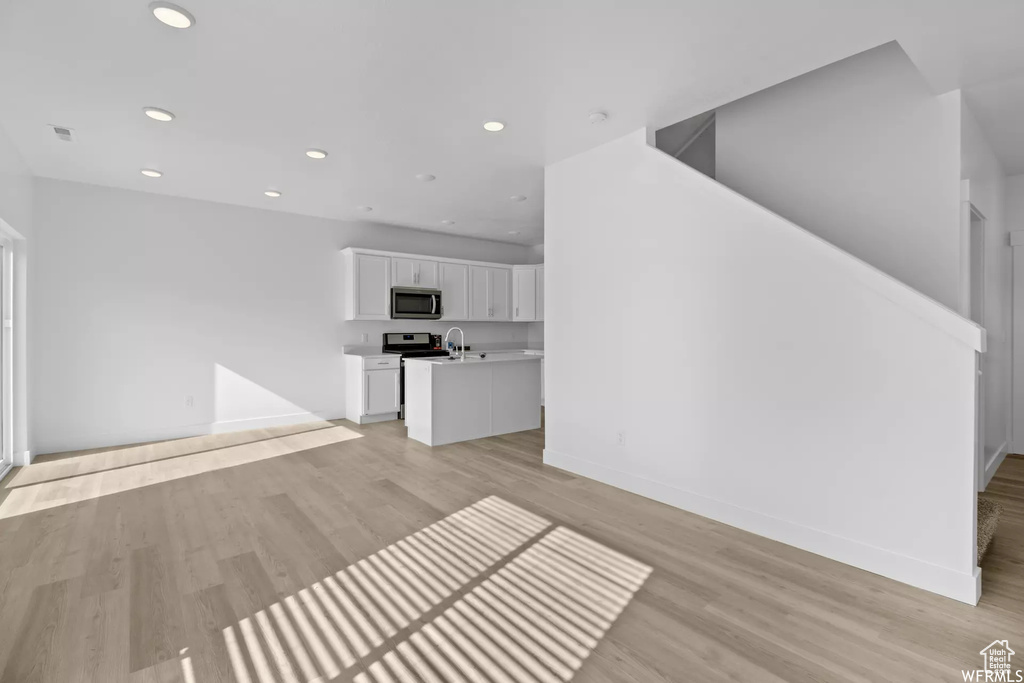 Unfurnished living room featuring light wood-type flooring and sink