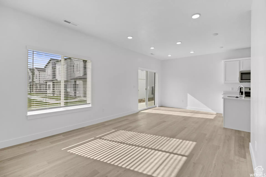 Unfurnished living room with sink and light hardwood / wood-style floors