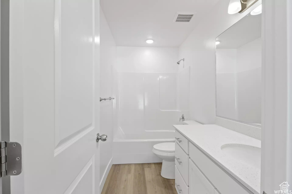 Full bathroom featuring shower / tub combination, wood-type flooring, toilet, and vanity