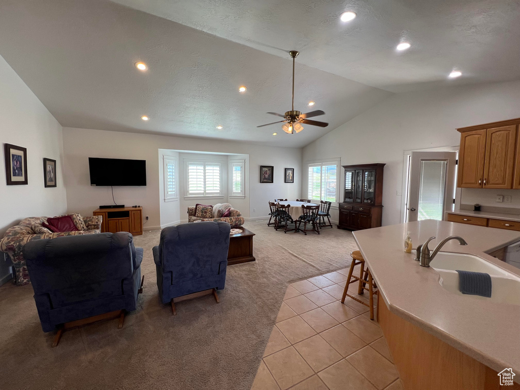 Living room with high vaulted ceiling, a textured ceiling, sink, ceiling fan, and light tile patterned flooring