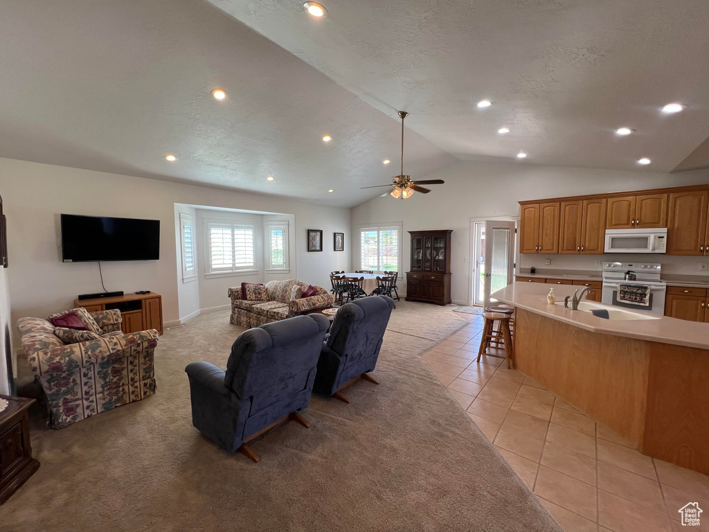 Tiled living room with a textured ceiling, ceiling fan, sink, and high vaulted ceiling