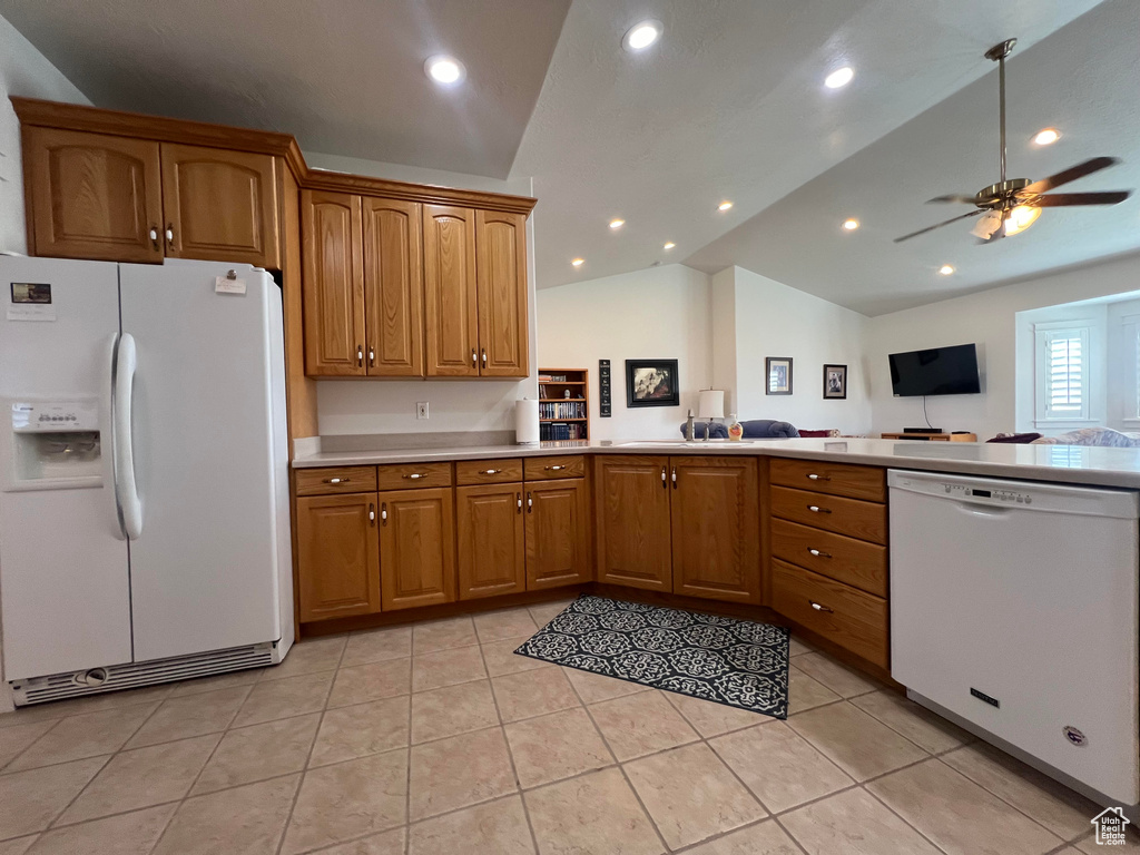 Kitchen with white appliances, light tile patterned floors, kitchen peninsula, ceiling fan, and lofted ceiling