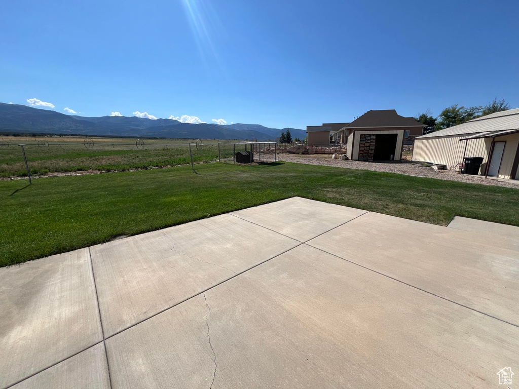 View of patio with a mountain view, a garage, and a rural view