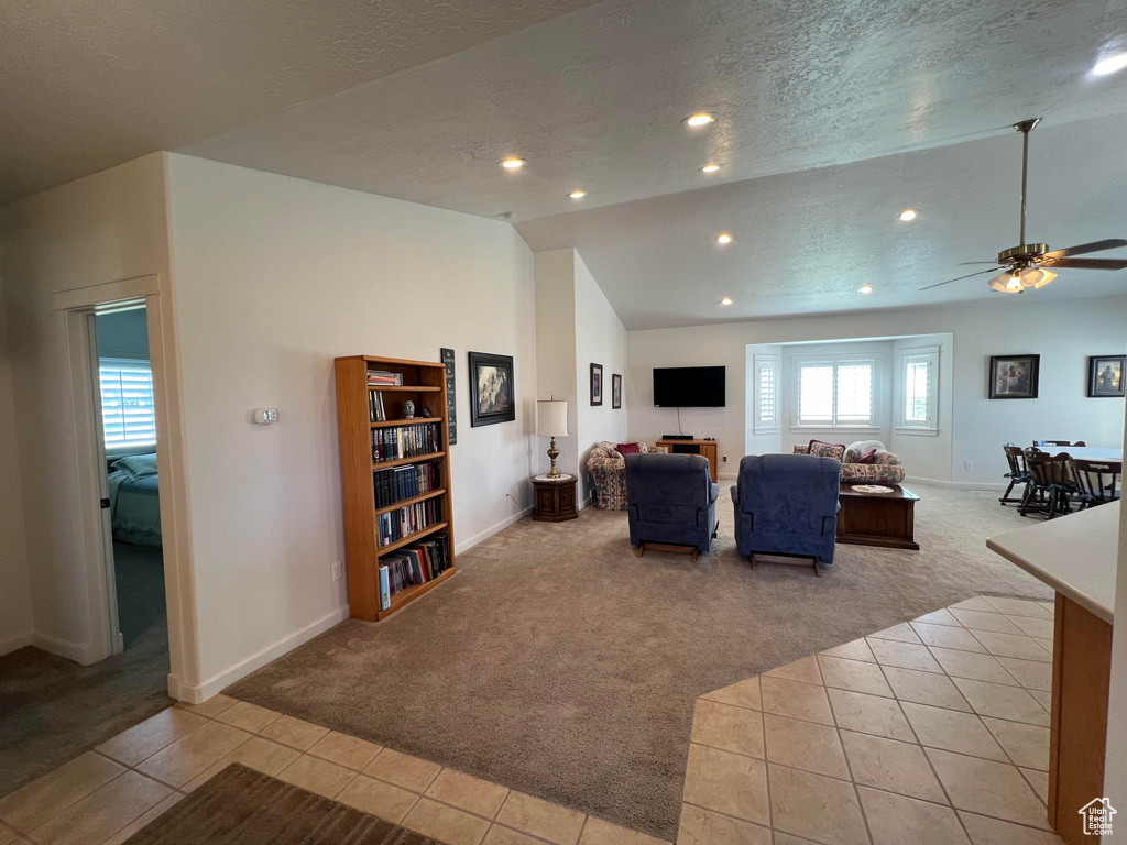 Tiled living room with a textured ceiling, ceiling fan, and vaulted ceiling