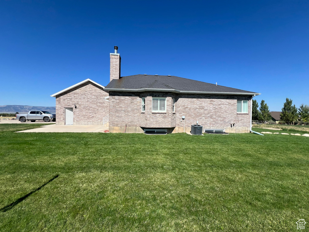 Rear view of property featuring a lawn, a patio, and central AC