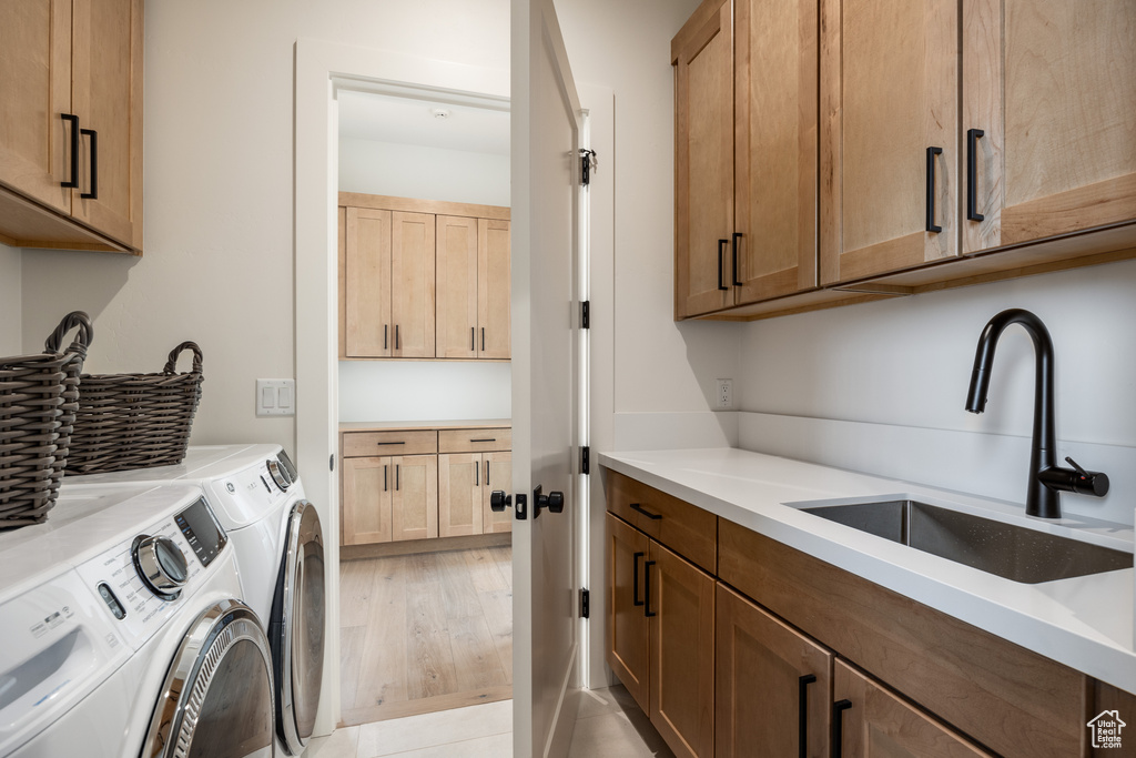 Washroom featuring separate washer and dryer, cabinets, light hardwood / wood-style floors, and sink