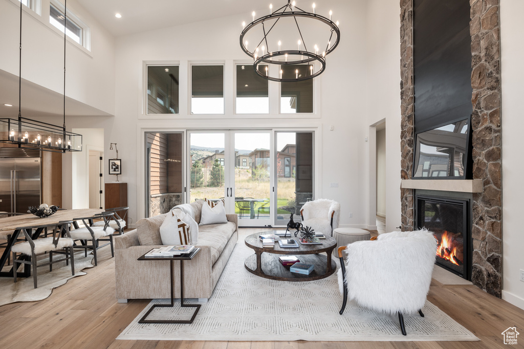 Living room with high vaulted ceiling, light wood-type flooring, and a stone fireplace