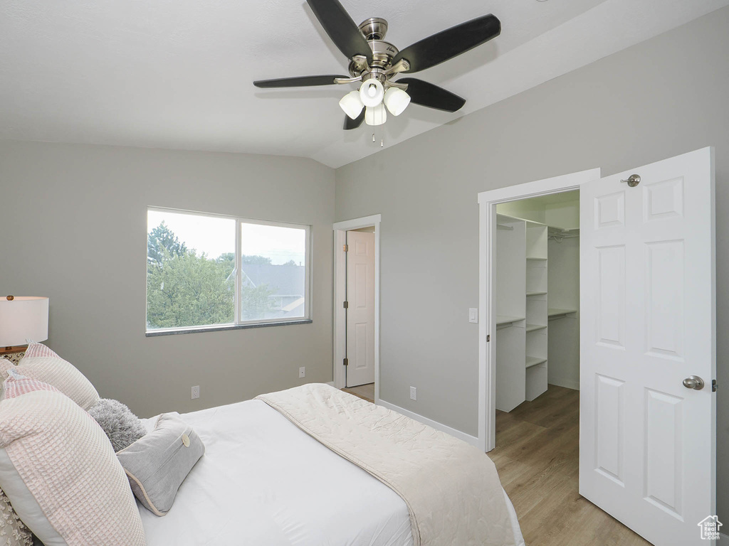 Bedroom with vaulted ceiling, light hardwood / wood-style floors, a closet, a spacious closet, and ceiling fan