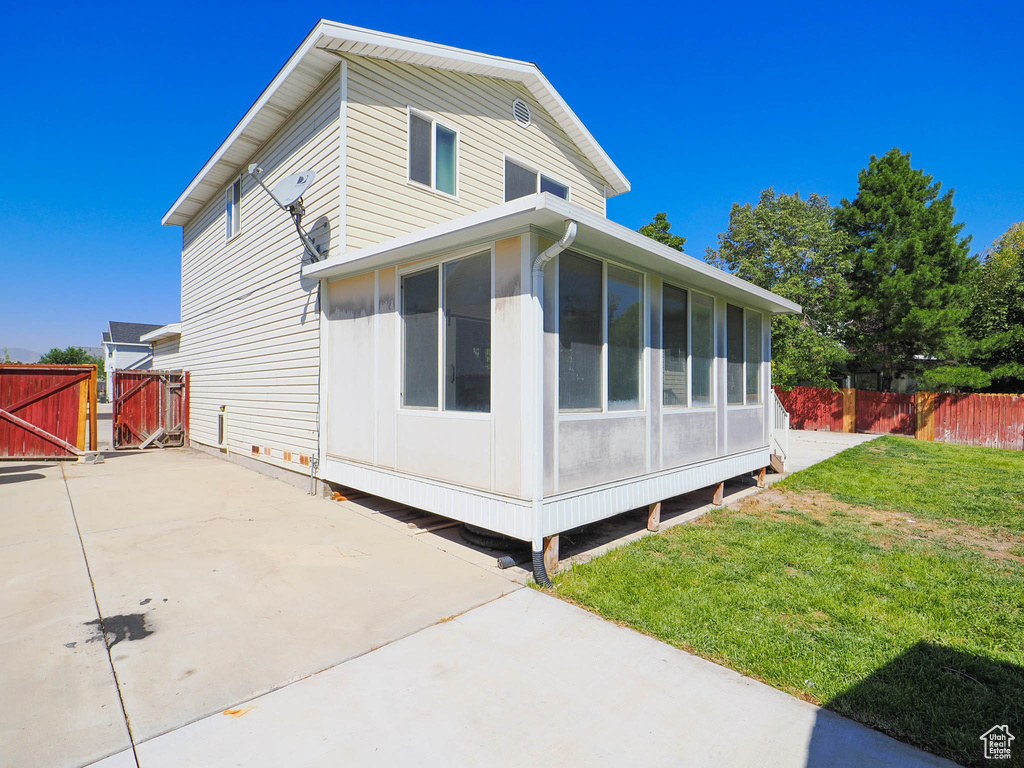 View of side of home featuring a sunroom, a yard, and a patio area