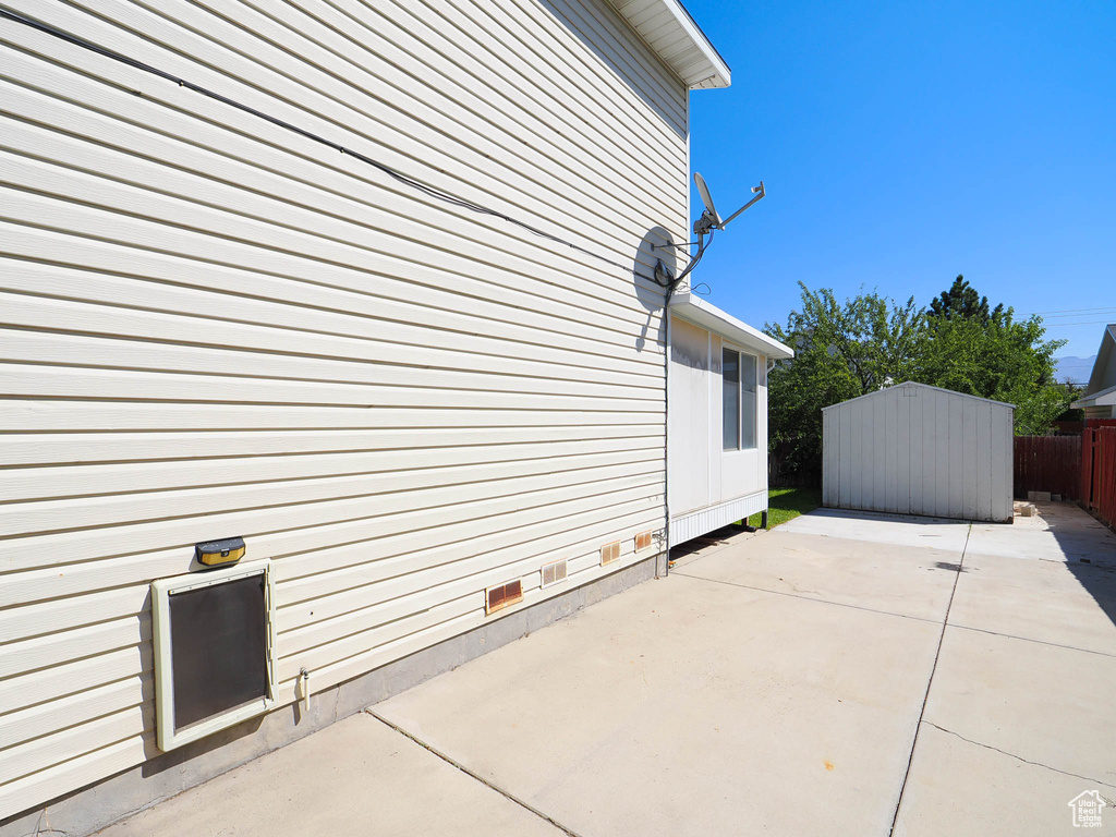 View of home's exterior with a storage unit and a patio