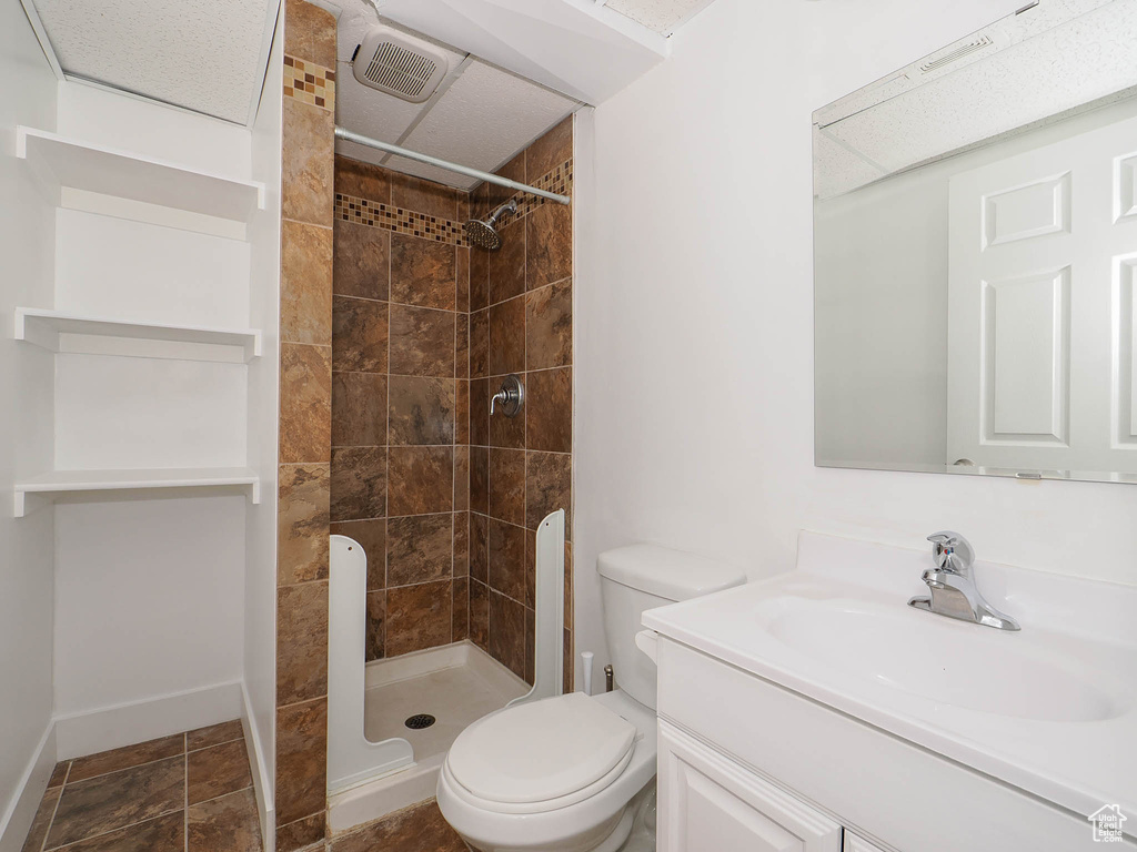 Bathroom featuring toilet, a tile shower, and vanity