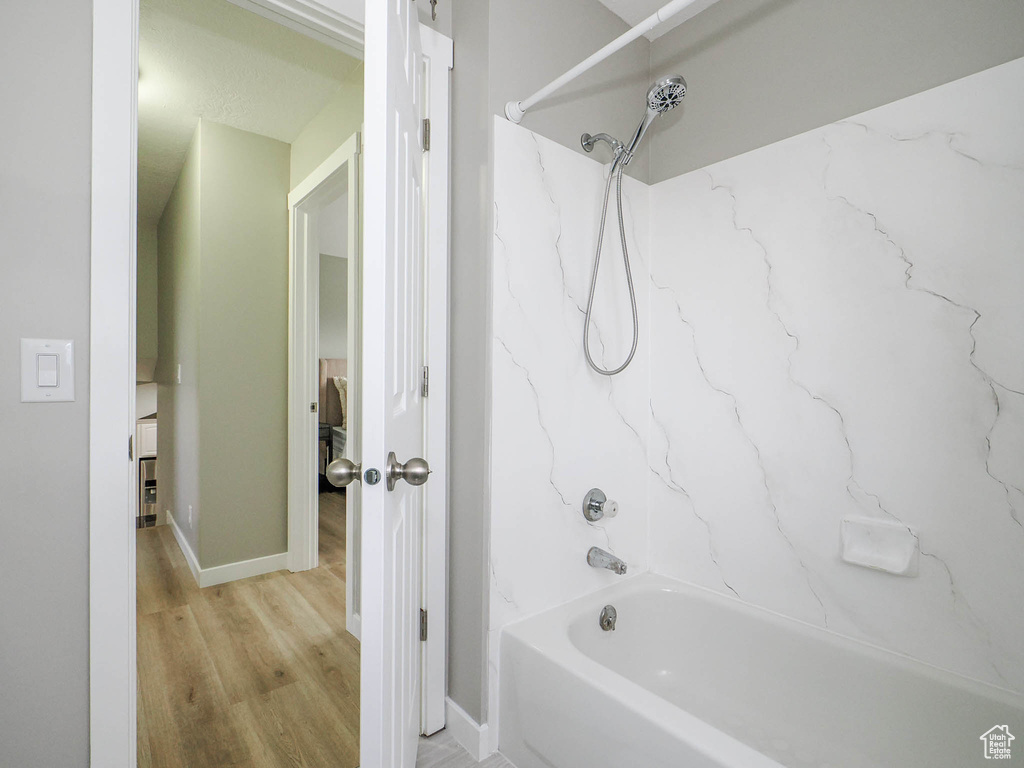 Bathroom with wood-type flooring and shower / bathtub combination