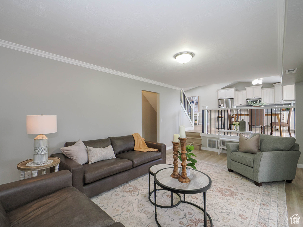 Living room with crown molding and light hardwood / wood-style flooring