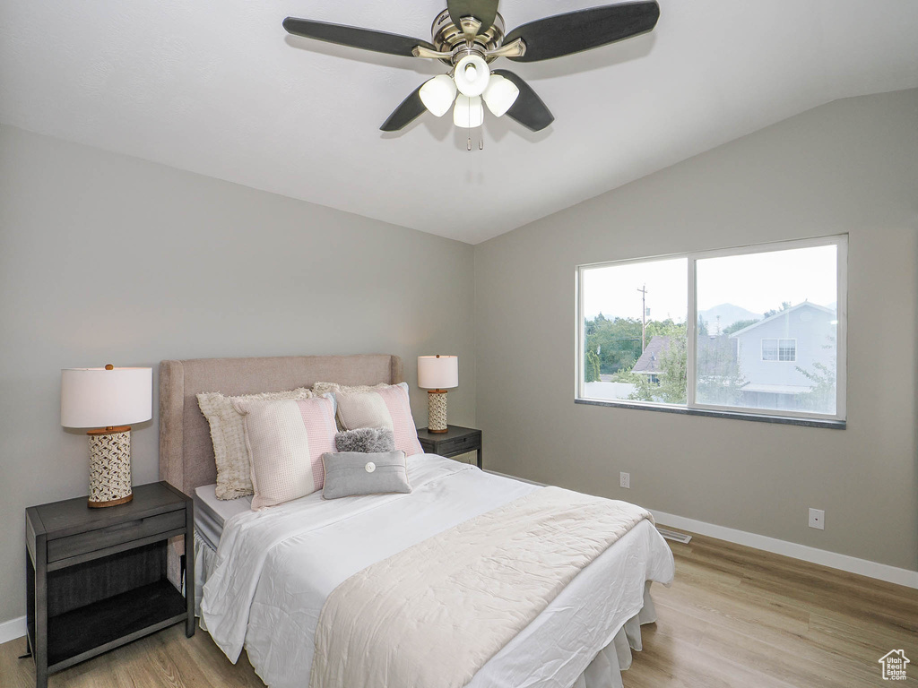 Bedroom with light wood-type flooring, vaulted ceiling, and ceiling fan