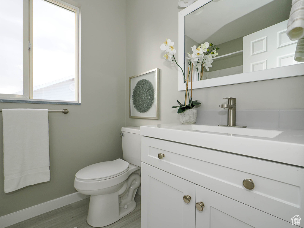 Bathroom with hardwood / wood-style floors, toilet, and vanity