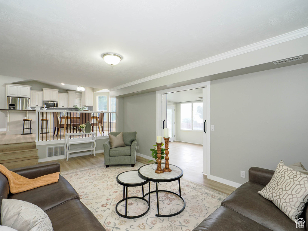 Living room with light wood-type flooring and crown molding