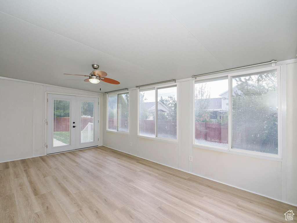 Unfurnished room featuring french doors, a wealth of natural light, ceiling fan, and light hardwood / wood-style floors