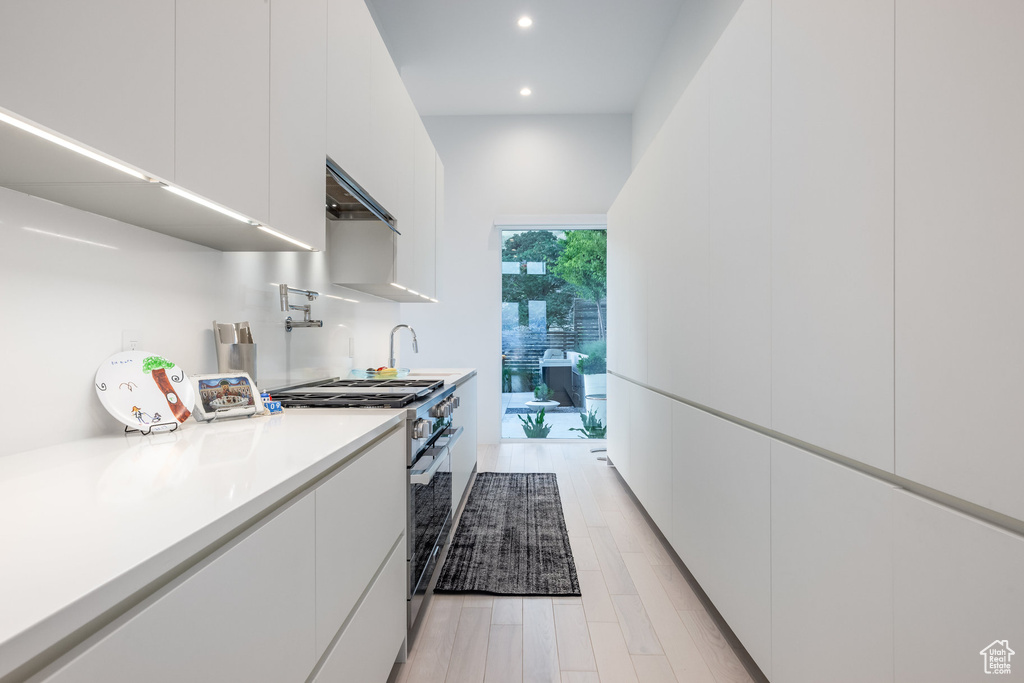 Kitchen featuring high end stove, light wood-type flooring, and white cabinets