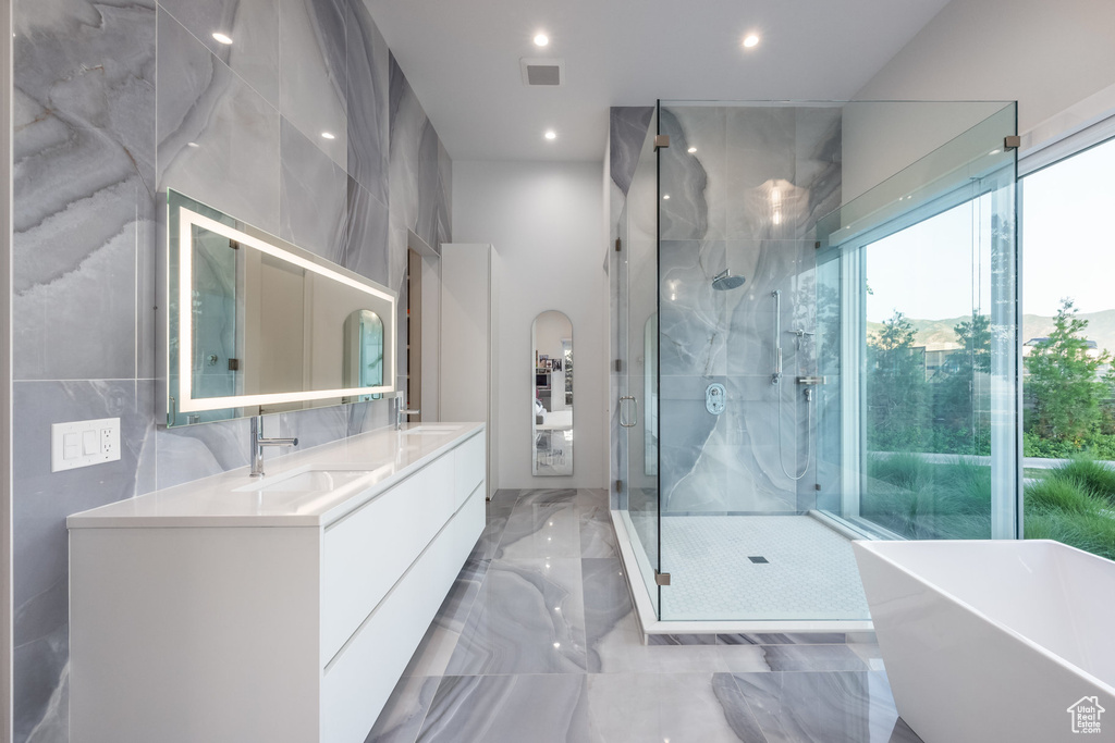 Bathroom with vanity, tile walls, and plus walk in shower