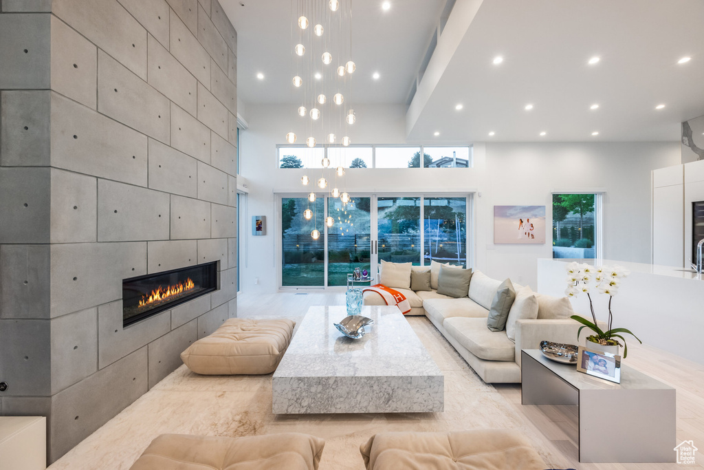 Living room with light wood-type flooring, beam ceiling, a high ceiling, and a tile fireplace