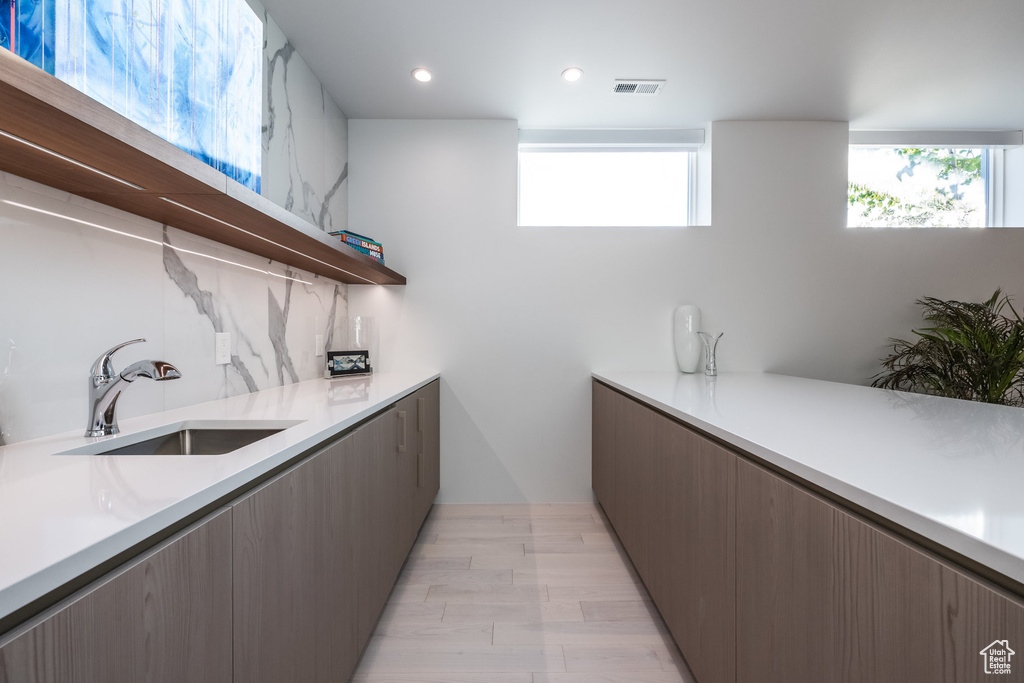 Kitchen featuring light hardwood / wood-style flooring, tasteful backsplash, and sink