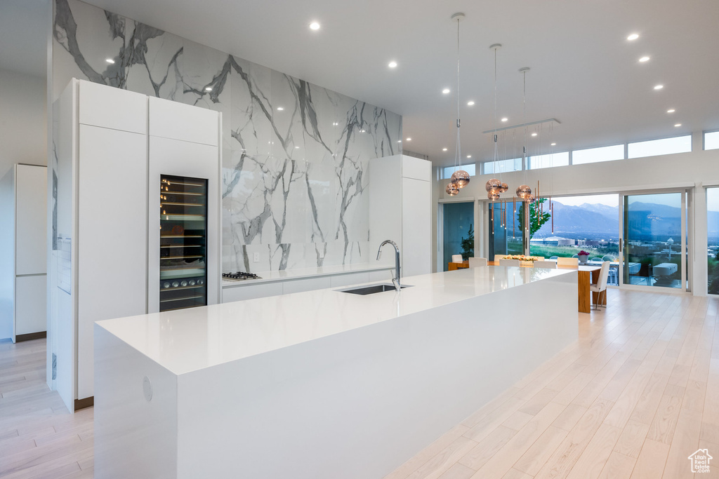 Kitchen with white cabinetry, a spacious island, sink, and hanging light fixtures