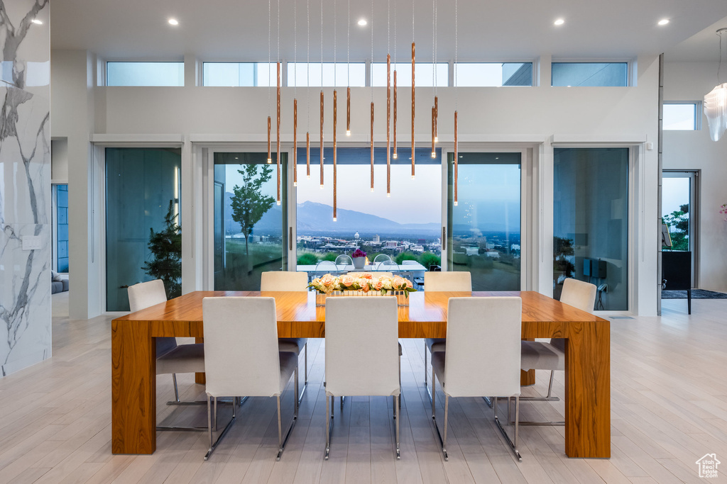 Dining area featuring light wood-type flooring, a wealth of natural light, and a towering ceiling