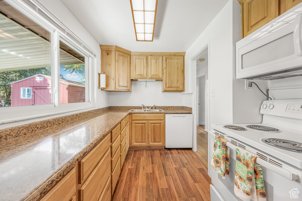 Kitchen featuring white appliances, light hardwood / wood-style flooring, sink, light brown cabinets, and light stone counters