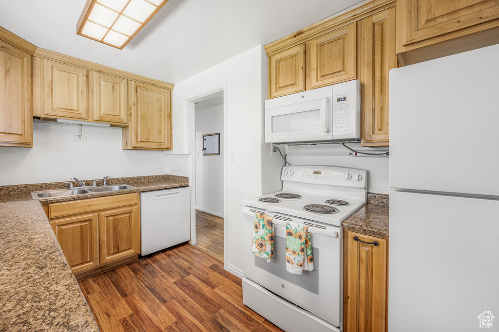 Kitchen featuring dark wood-type flooring, white appliances, light brown cabinets, and sink