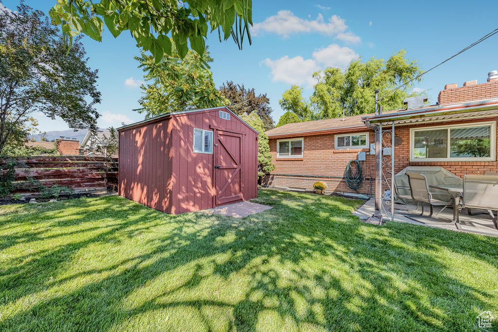 View of yard with a storage unit and a patio area