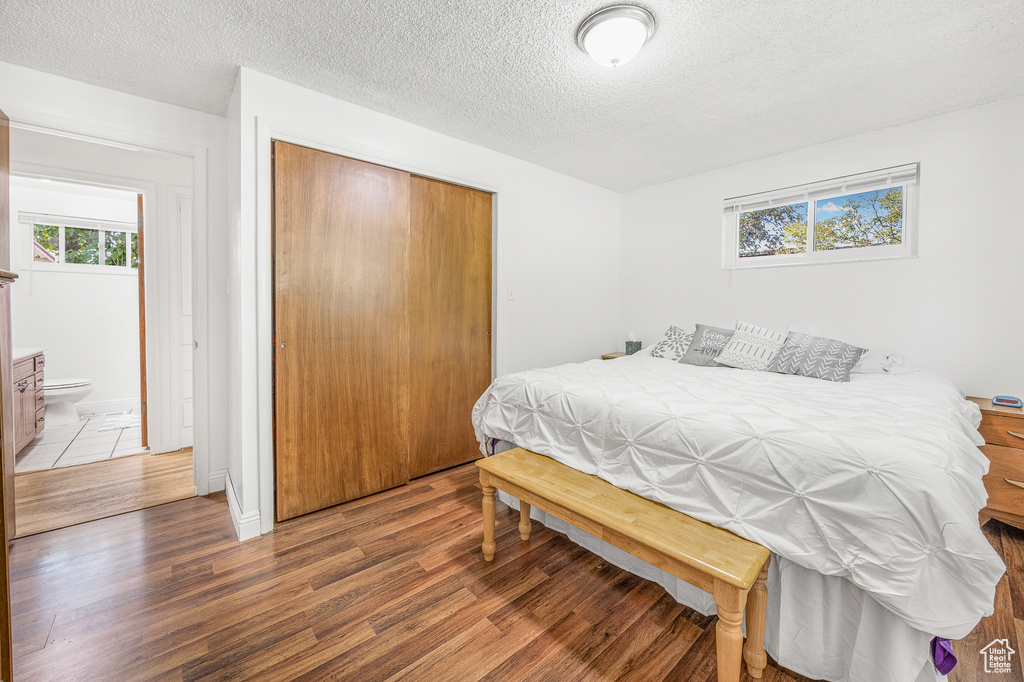 Bedroom featuring hardwood / wood-style floors, a closet, a textured ceiling, and ensuite bath