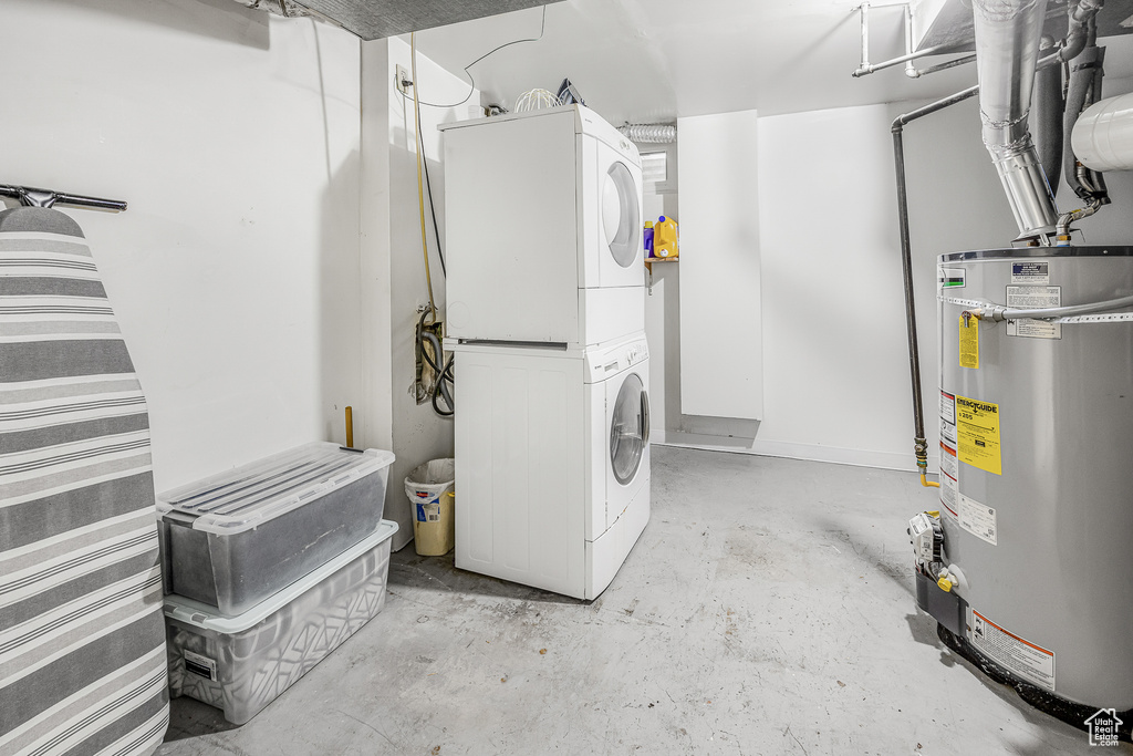 Laundry room with gas water heater and stacked washing maching and dryer