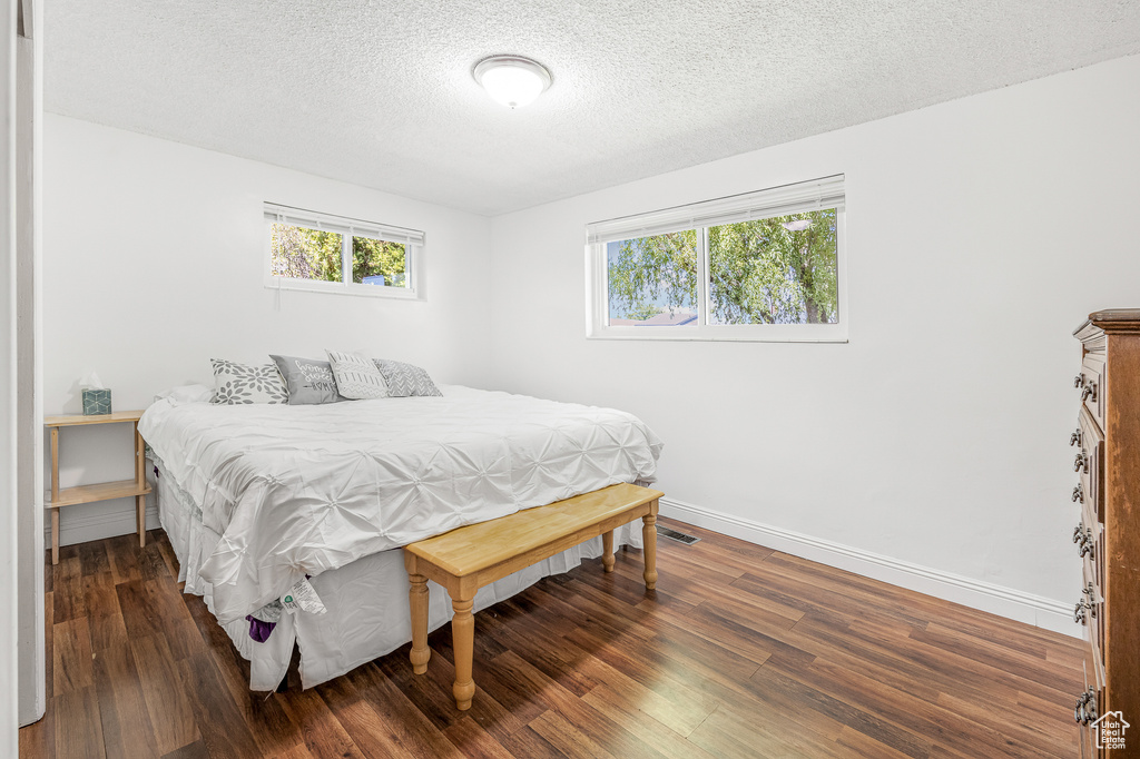 Bedroom with a textured ceiling and dark hardwood / wood-style floors