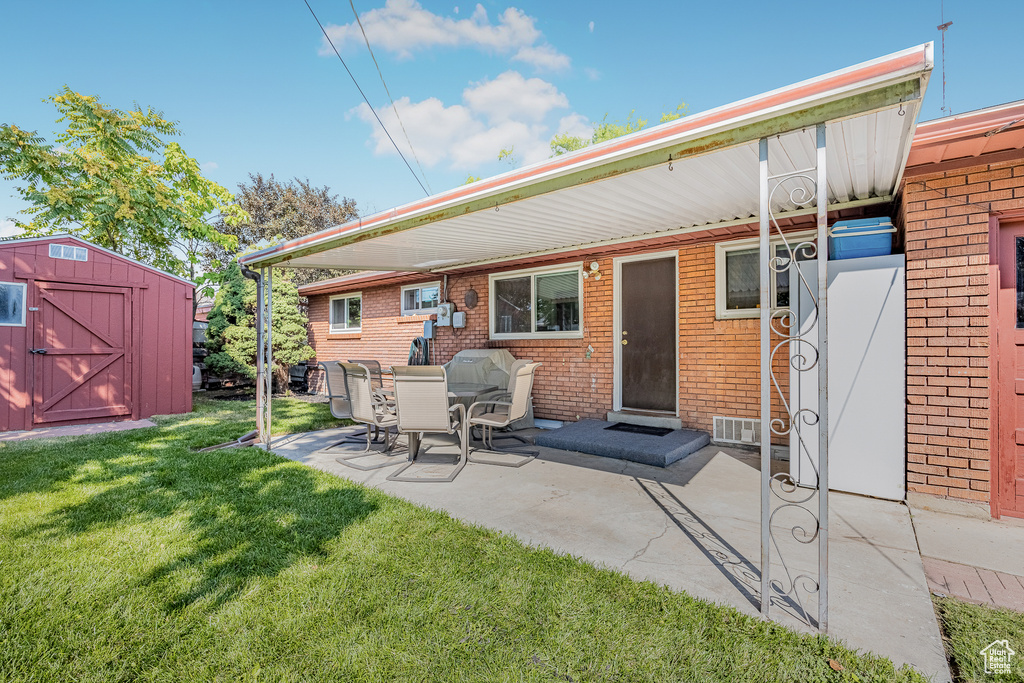 Rear view of property featuring a storage shed, a yard, and a patio area