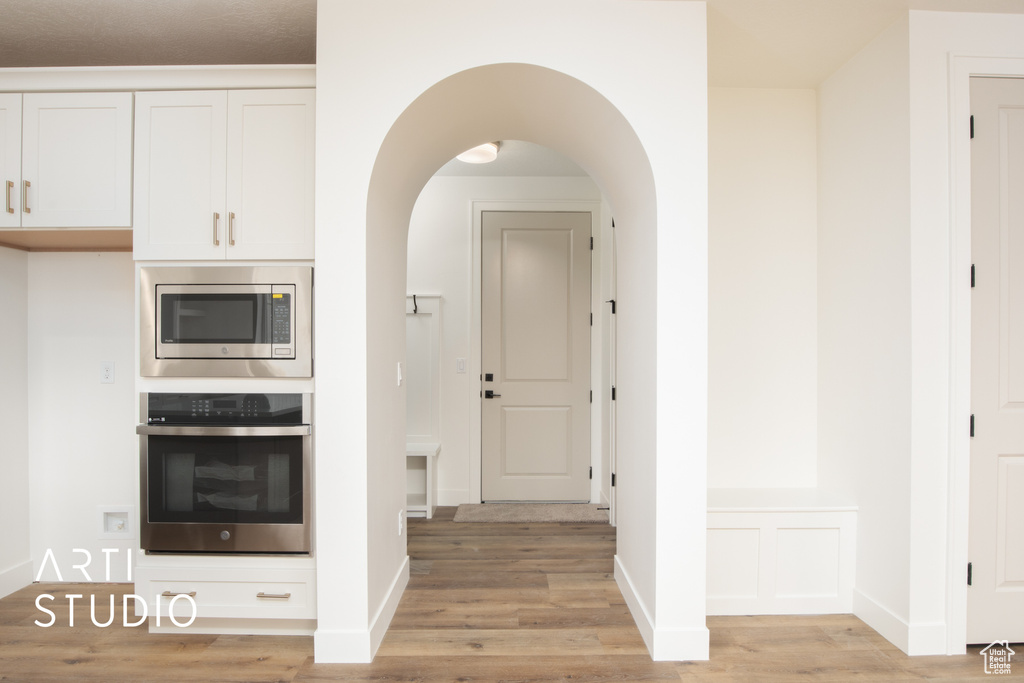 Kitchen with light wood-type flooring, white cabinetry, and stainless steel appliances