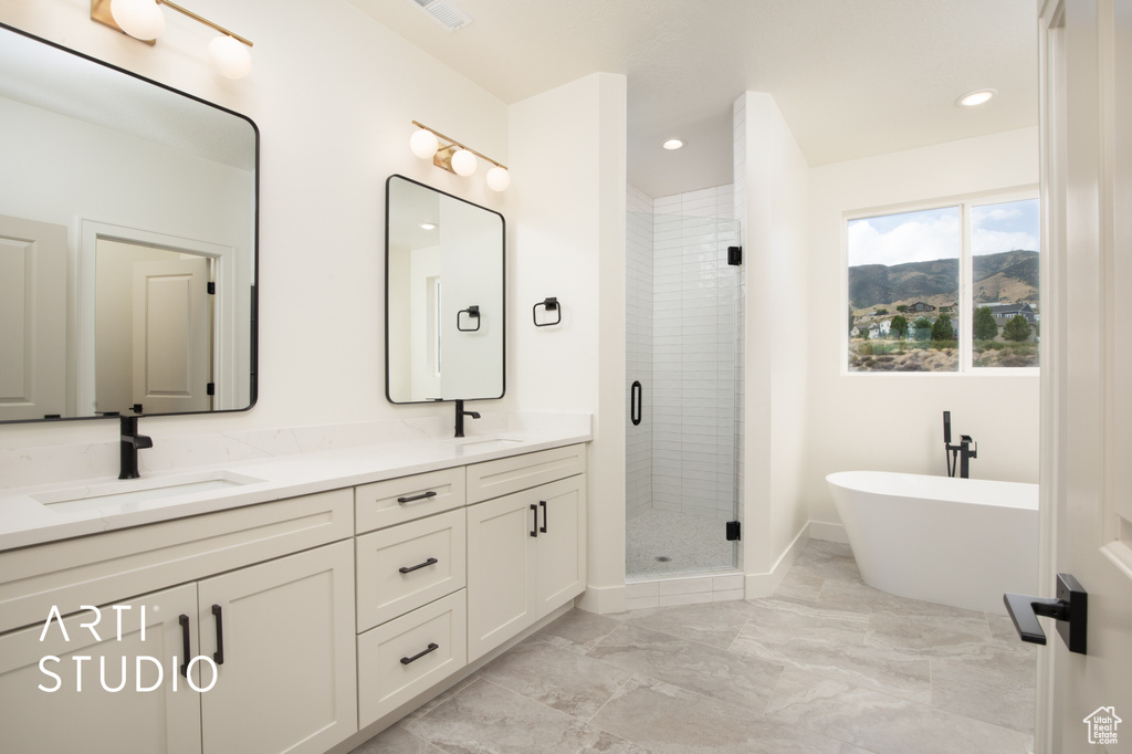 Bathroom featuring vanity and separate shower and tub