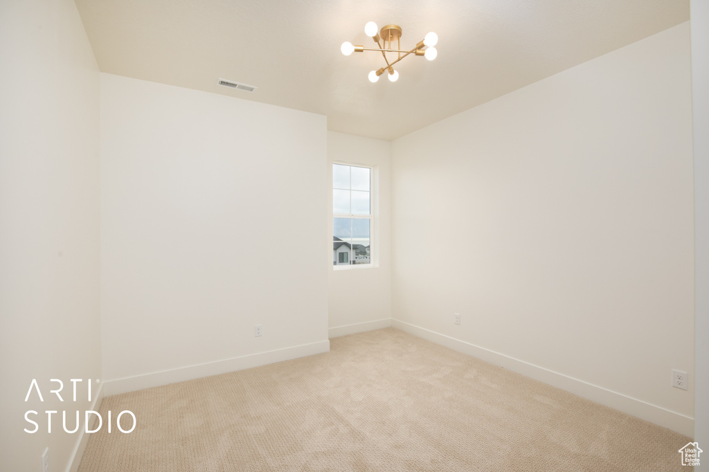 Carpeted spare room with a notable chandelier