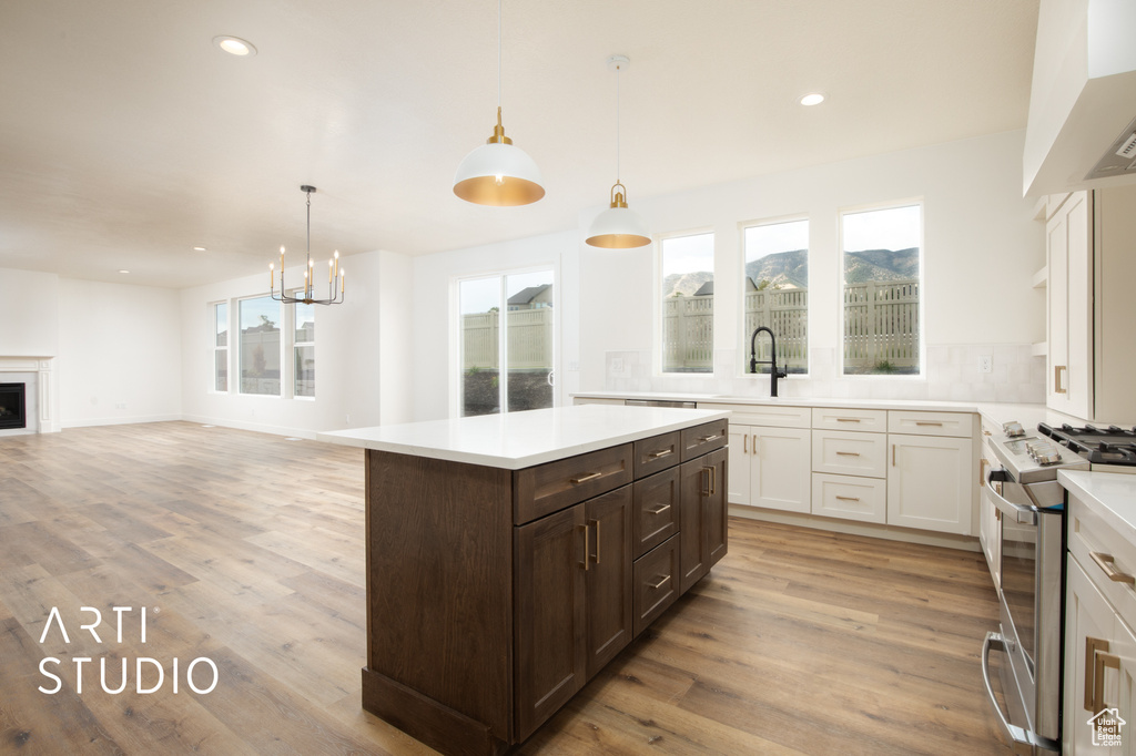 Kitchen with white cabinets, gas stove, a center island, light hardwood / wood-style floors, and premium range hood