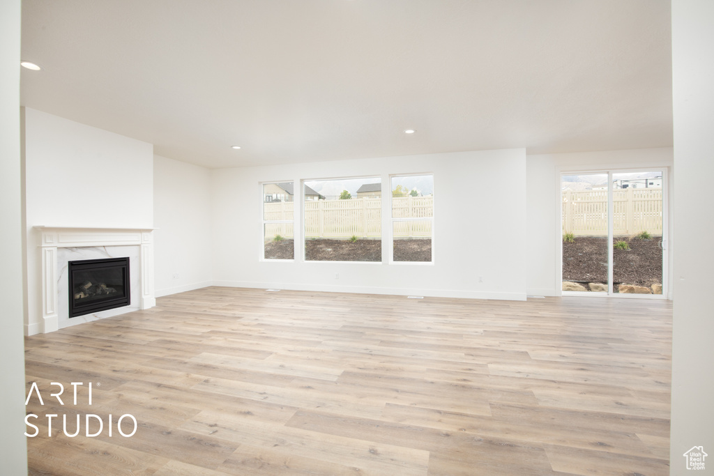 Unfurnished living room with plenty of natural light, light hardwood / wood-style floors, and a premium fireplace