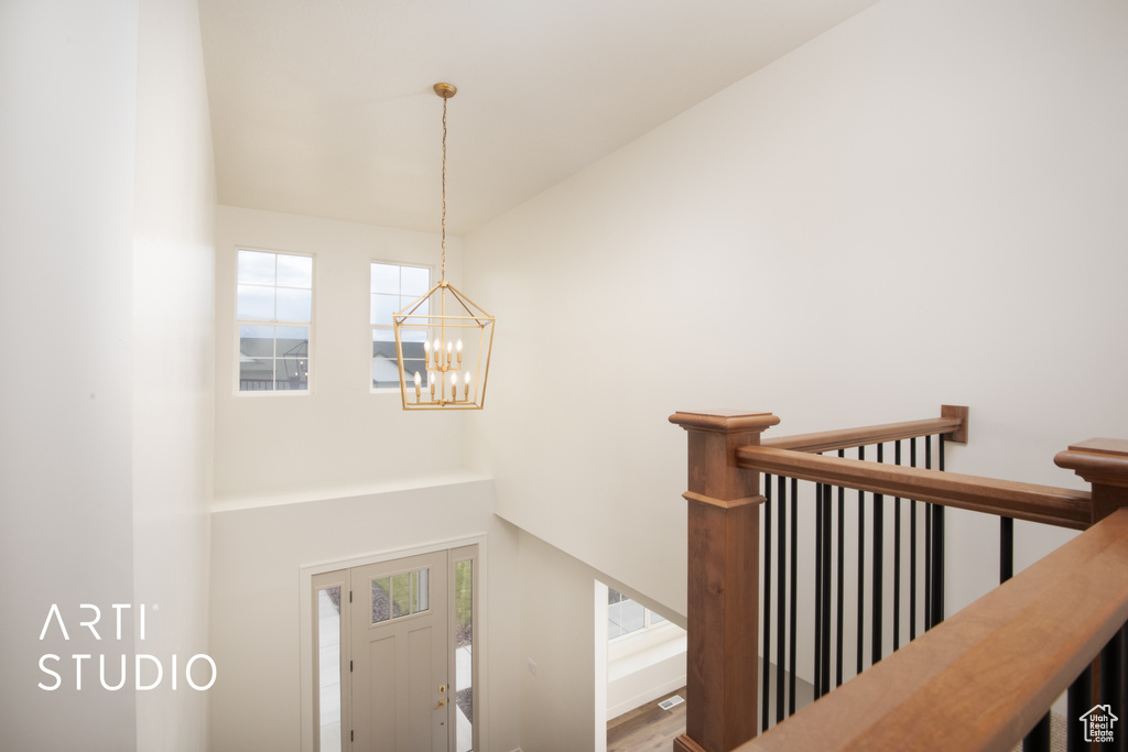 Stairs with a wealth of natural light, a notable chandelier, and hardwood / wood-style flooring