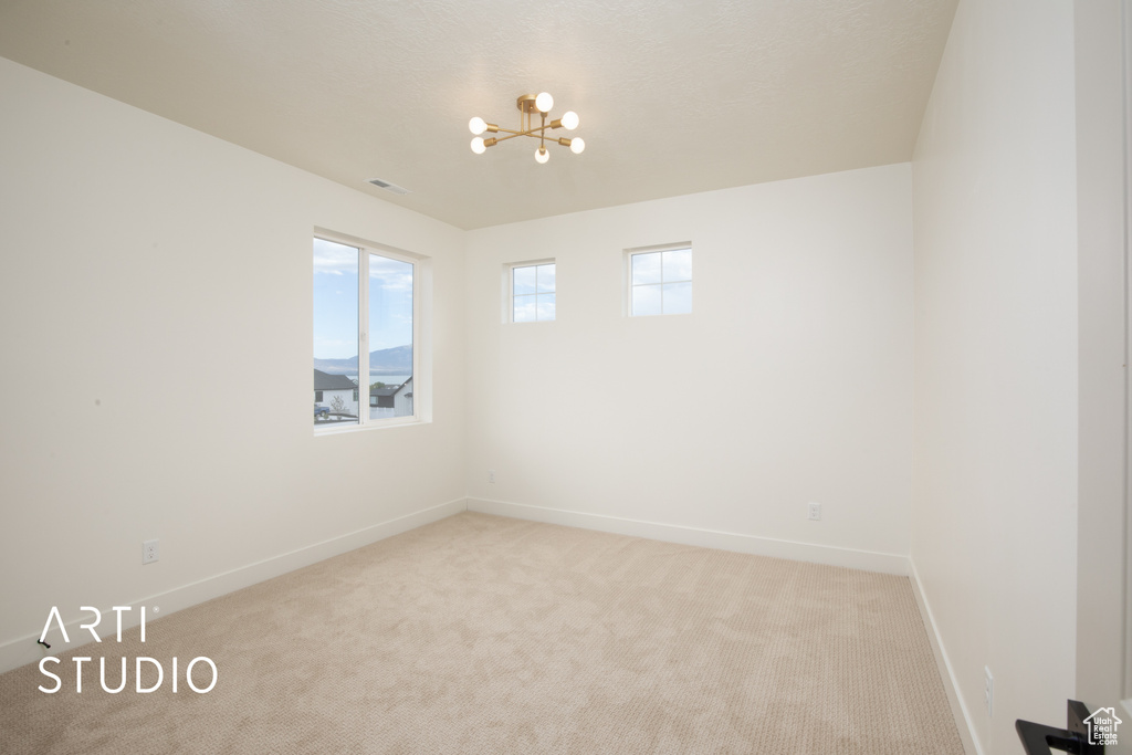 Spare room featuring a notable chandelier and light carpet